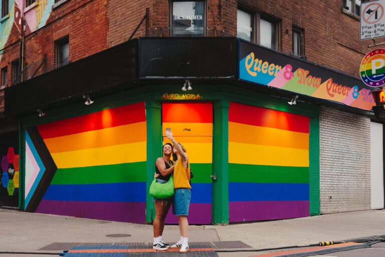 couple taking selfie in front of rainbow hoarding on building